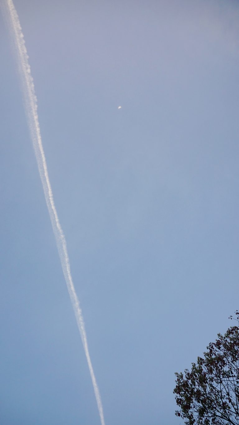 宵の月にかかる飛行機雲